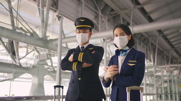 Airliner pilot and air hostess wear face mask walking in airport terminal to airplane during Covid19