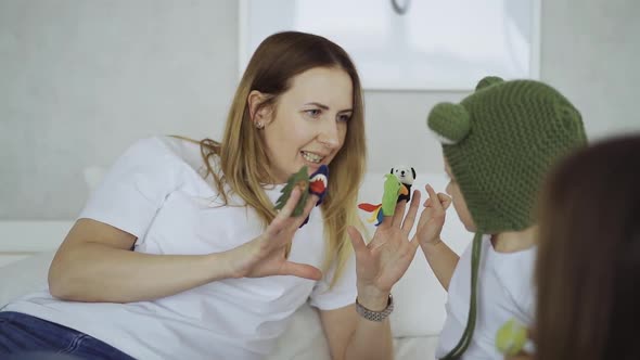 adorable mother and her children, daughter and little son play toys on fingers