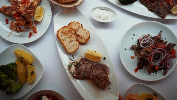 Overhead View of a Hand Serving Meat and Grilled Bread Dish on a White Plate