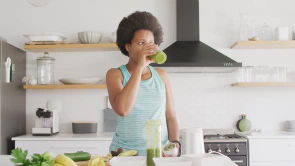 Happy african american woman preparing healthy drink in kitchen