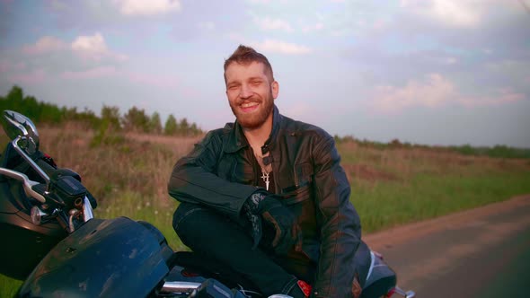 Young Man Sitting on Motorcycle on the Road at Sunset Slow Motion