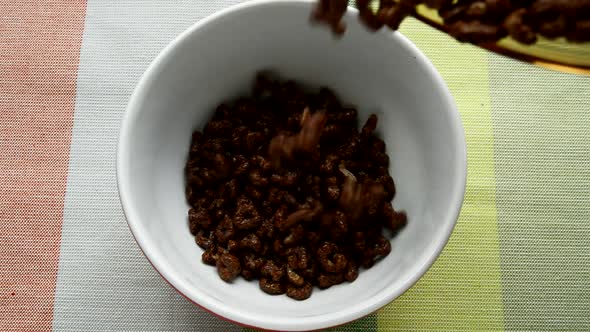 HD video,chocolate cornflakes in the form of an alphabet, poured into a white bowl. Top view of cris