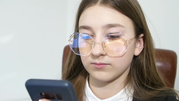 Teenage Girl in Formalwear Talking on Cell Phone Sitting in the Office on a White Background