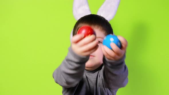 Cheerful Happy Boy with Bunny Ears on Head is Playing with Easter Colorful Eggs