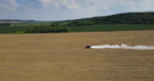 A Tractor Drives Fertilizer Across A Mown Field 