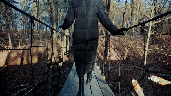 Woman Walking On Suspension Bridge. Tourist Walkway In Forest. Traveler Explore Forest.Wooden Bridge