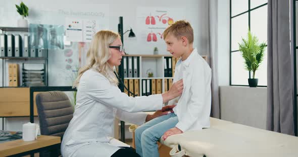 Doctor Checking Heartbeat and Lungs of Teen Calm Boy which Visiting Her Medical Cabinet