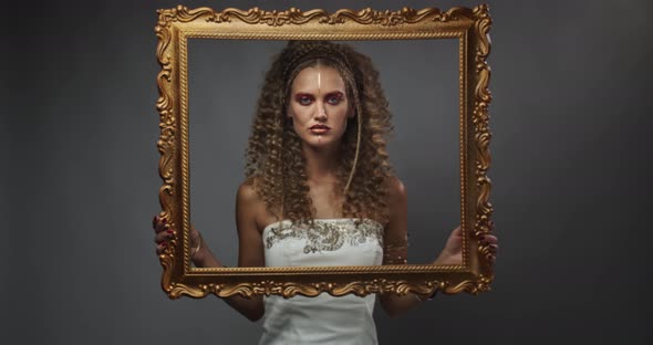 Elegance and Fashion, Young Woman with Curly Hair Is Posing with a Picture Frame