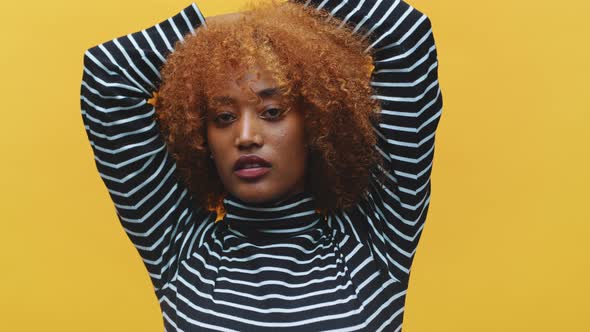 Young African American Black Woman with Curly Afro Hair Posing in Front of Yellow Background with