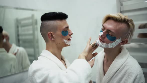 Male Couple Having Fun Applying Shaving Foam Doing Morning Routine Together in Bathroom