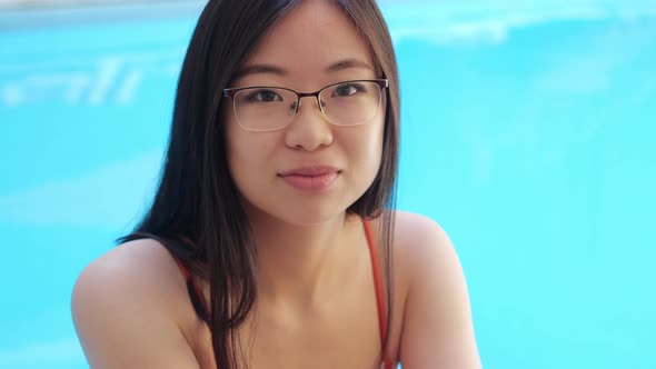 Closeup View of Asian Ethnicity Placed Lady in Glasses Sitting in Poolside at Home Hotel Spa