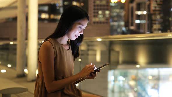 Woman looking at mobile phone in city at night 