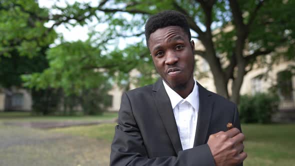 Confident Stylish Man Smelling Cigar Looking at Camera Standing Outdoors