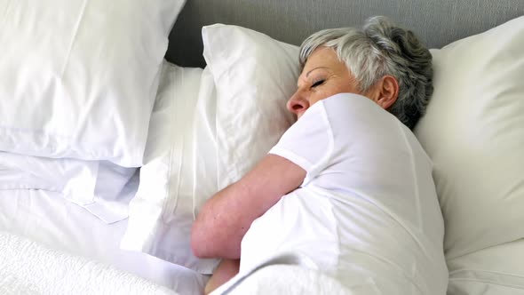 Senior woman sleeping on bed in bedroom