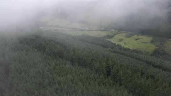 Drone shot emerging out of a cloud, revealing a green lush valley.