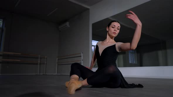 Young Woman Sitting on Floor Performing Ballet Movements Lying Down