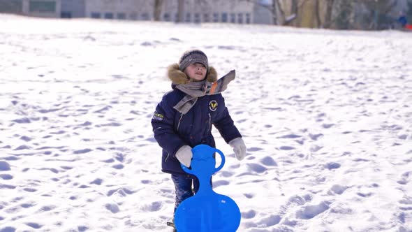 child boy having fun, playing and laughing on snowy winter walk in nature.