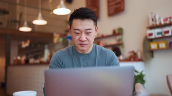 Happy Asian young man working by laptop
