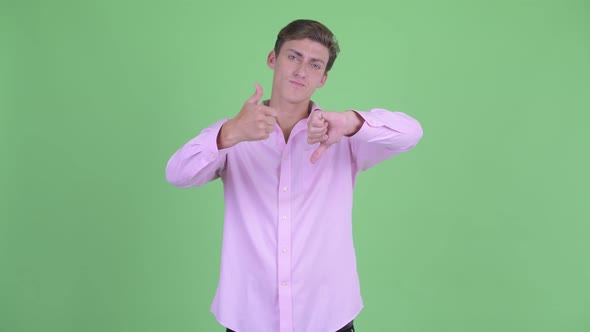 Confused Young Businessman Choosing Between Thumbs Up and Thumbs Down