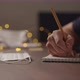 Slow Motion Orbit Shot Closeup Man Writes Shopping List Notepad Pencil Under Warm Light Evening - VideoHive Item for Sale
