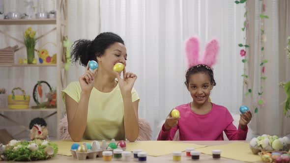 Mom and Daughter with Funny Bunny Ears Laugh and Have Fun with Colored Eggs