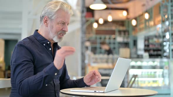 Video Chat on Laptop By Old Man in Cafe