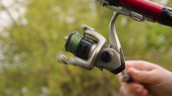 Slow Motion of a Woman's Hand Spinning a Fishing Rod Reel