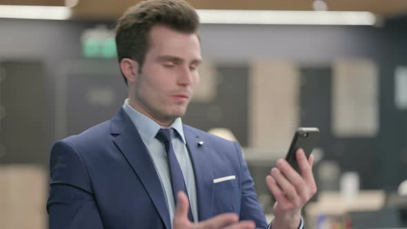 Portrait of Businessman Reacting to Loss on Smartphone