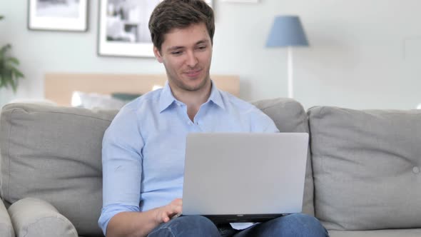 Online Video Chat on Laptop By Handsome Young Man Sitting at Creative Workplace