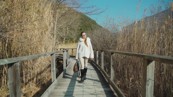 Young Stylish Woman Walks on Wooden Bridge Build Over Pond