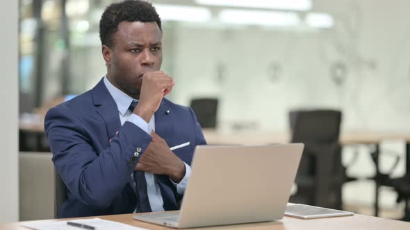 African Businessman Coughing While Using Laptop in Office