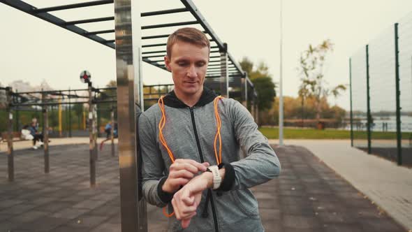 Man Measuring Pulse on Sports Watch During Training Jumping to Ropes Outdoors