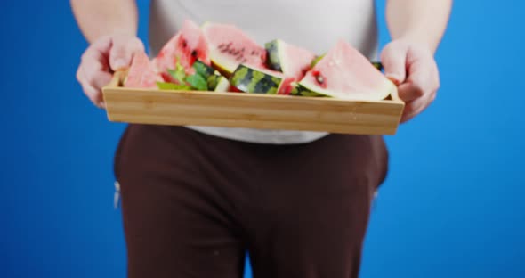 A Man Holding a Tray with Slices of Watermelon. 