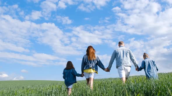 Happy Family Holding Hands Walking on a Green Field