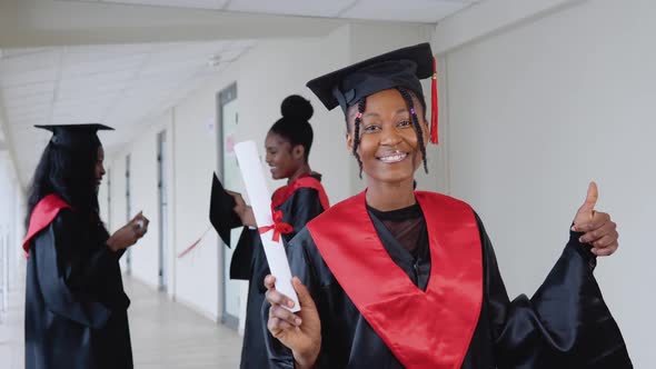 A Joyful Female Graduate with a Diploma in Hand Stands at the University Against the Background of