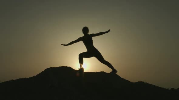 Silhouette of Woman Practicing Yoga Alone on Top of Mountain in the Evening
