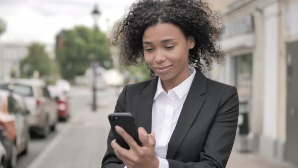 African Businesswoman Cheering Success on Smartphone Standing Outdoor