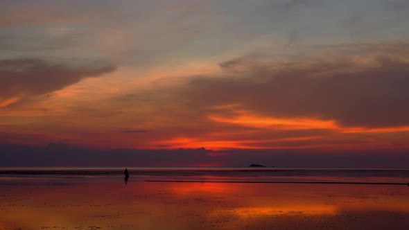 Asian Fisherman Walking on the Beach at Low Tide Silhouette of Two People at Sunset