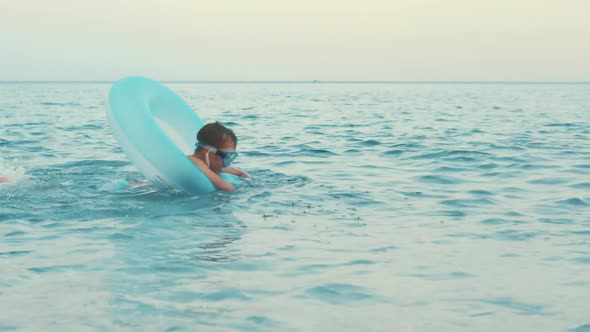 Little Boy Swimming on Inflatable Circle at Sea. Kid Hitting Water with Feet