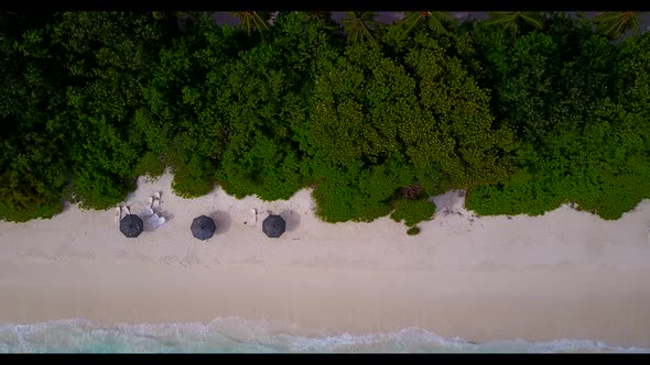 Aerial drone shot sky of perfect seashore beach adventure by shallow ocean with bright sand backgrou