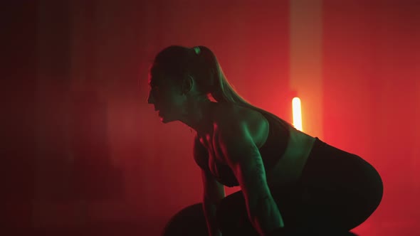 Young Powerful Woman is Lifting Barbell in Gym Training Overnight for Preparing to Competition