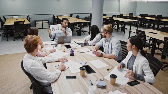 Ceo Male Showing Diagram Explaining Details of Startup Project to Team of Diverse Colleagues Sitting