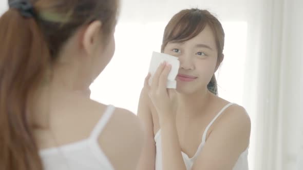 Beautiful young asian woman smile and joy with skin care use oil blotting paper on face.