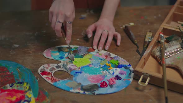 Female Artist Mixing Acrylic Paints on Palette in Art Studio