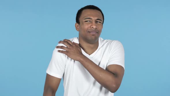 Young African Man with Soulder Pain Blue Background