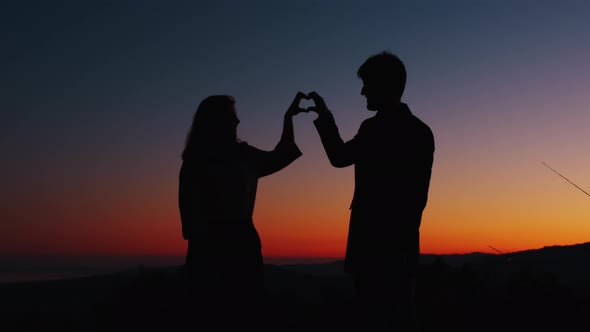 Silhouette of couple making heart symbol