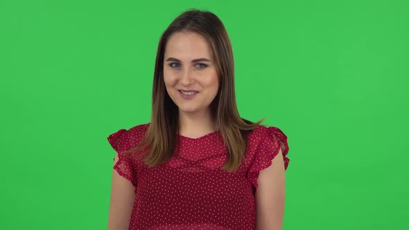 Portrait of Tender Girl in Red Dress Is Coquettishly Smiling While Looking at Camera. Green Screen