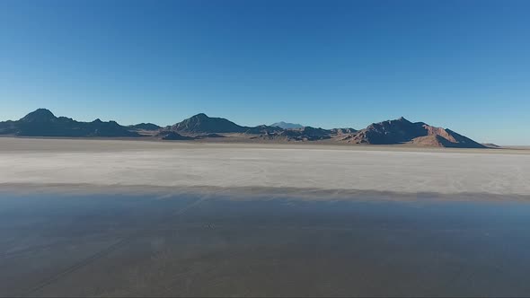 An aerial drone shot reveals smooth water covering the white salt of the Bonneville Salt Flats and d