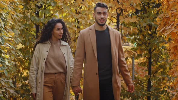 Young Hispanic Couple Walking in Autumn Forest Curly Brunette Holds Hand of Bearded Husband Man