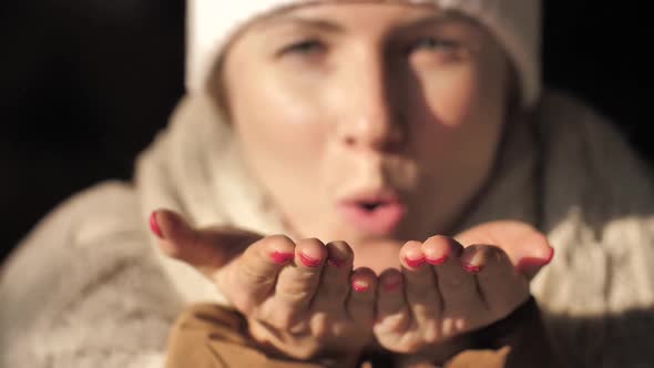 Young Woman Blowing Many of Pieces of Silver Glitter from Hand